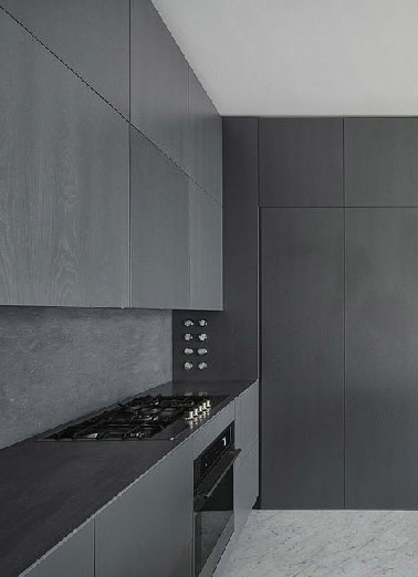 Bien pensé l’aménagement de cette cuisine qui se sert de la disposition des meubles pour faire varier l’intensité du noir mat en fonction de la lumière du jour. Les grands carreaux de marbre gris complètent le design de cette cuisine exceptionnelle.  