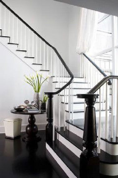 Majestueuse, grandiose la déco d'un grand escalier d'une maison ancienne peint en noir pour former un prolongement avec le sol de l’entrée. Une charmante déco modernisée en noir et blanc. 