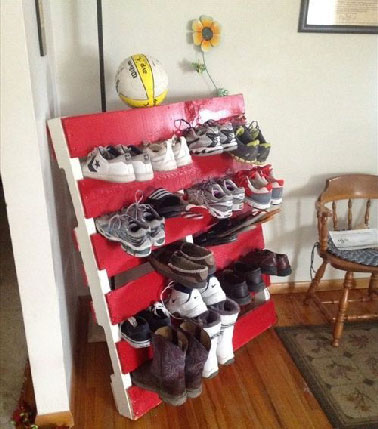 Un aménagement de studio astucieux avec un rangement des chaussures glissées dans une palette bois peinte en rouge et blanc
