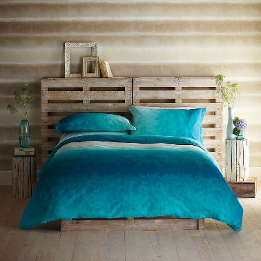Une tête de lit sans transformation des palettes. Simplement posées à la verticale sur le mur et le bois laissé brut pour créer une unité couleur avec les murs et parquet. 