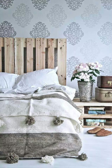 Unité dans la déco de la chambre avec une tête de lit en palette posée debout et une table basse faite de 2 palettes superposées qui sert de table de chevet.