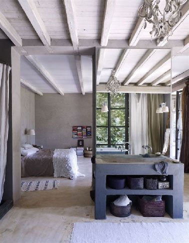 Largement ouverte sur le jardin grâce à 4 baies vitrées, une chambre parentale qui mise sur les matériaux pour créer une ambiance zen propice à la détente. Séparée de l’espace de la chambre par une petite cloison, la salle de bain met le focus sur le meuble plan vasque fabriqué en béton ciré.