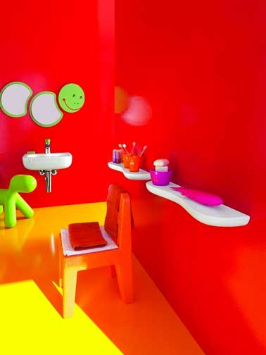 Une déco couleur salle de bain qui donne aux enfants une dose de bonne humeur dès la toilette du matin. Un rouge brillant sur les murs, jaunes sur le sol et du vert anis avec un miroir rigolo et un chien gonflable Fatboy