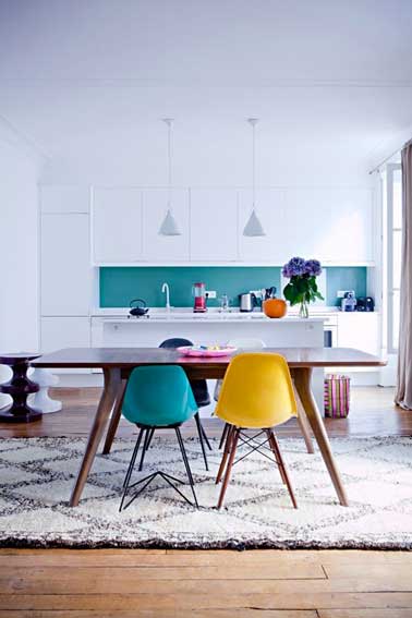 Une déco cuisine scandinave  blanche réveillée par une crédence peinte dans un lumineux bleu turquoise qui trouve son écho dans une des chaises dépareillées autour de la table.