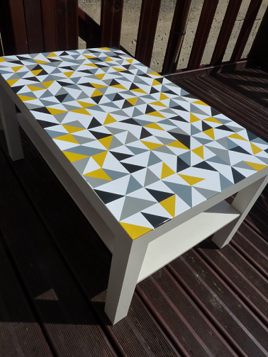 Cette table banale a été customisée grâce à des morceaux d'adhésifs de couleurs. Résultat : une table déco aux formes géométriques au style très actuel.