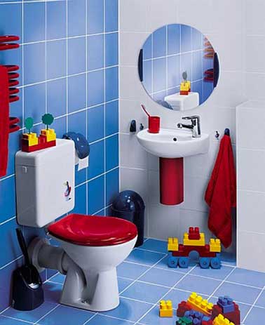 Des couleurs déco idéales pour une salle de bain ludique pour enfant en bas âge. S’inspirant des couleurs des Légo, un carrelage bleu et blanc en mural et sol, abattant de WC et accessoires de toilette rouge vif autour d’éléments sanitaires aménagées à sa taille.