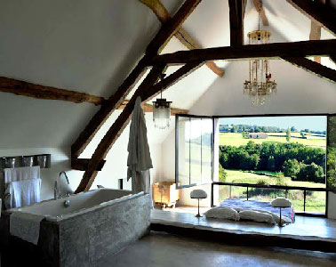 Une vue panoramique de rêve depuis le lit de cette chambre parentale relevé de quelques centimètre par l’estrade. La baignoire îlot installée dans la seconde partie de la chambre invite à la détente. 