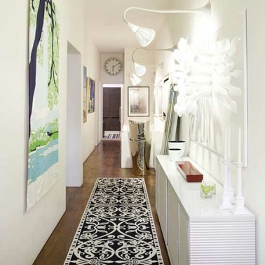 Dans ce couloir la lumière donne le relief à la déco immaculée. Un tapis et des tableau complètent l'aménagement.