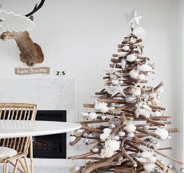Dans une ambiance déco scandinave, un sapin de Noël en bois flotté avec des branches entremêlées et des objets déco blancs tout doux c’est chic.
