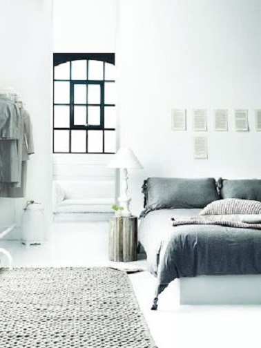 Dans une chambre blanche, le gris sur un tapis en maille ou un ensemble de linge de lit donne du caractère à la pièce et un contour de fenêtre noir apporte un effet design.