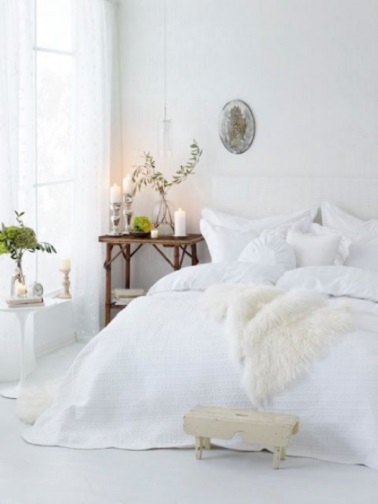 Cette chambre cocooning blanche joue avec la luminosité pour créer une ambiance cosy voluptueuse. Une grosse couette et une peau de mouton réchauffent l'atmosphère.