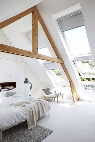 Sous les toits, cette chambre toute blanche est très lumineuse grâce à ses grandes fenêtres. La charpente en bois apporte par ailleurs de la chaleur à l'ambiance éthérée.