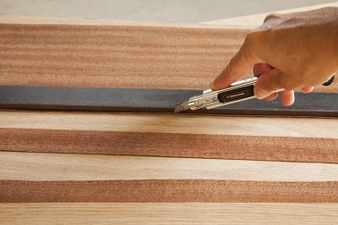 Pour réaliser le décor du sapin de Noël en bois, découper à l'aide d'un cutter des formes dans des feuilles de placage de différentes essences pour encore plus d'effet. 