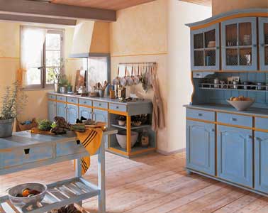 Patiner des meubles de cuisine en bleu sur les portes et tiroirs et orange sur les moulures et montant une bonne idée pour relooker une cuisine rustique. Base et Patine Libéron.