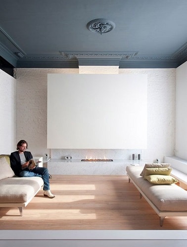 Peindre un plafond en gris-bleu dans un salon design blanc, ça donne de l'élégance et ça réchauffe la déco de la pièce. En plus ça met en valeur les moulures du plafond.