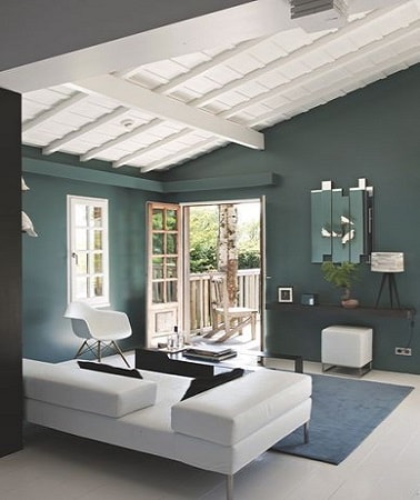 Dans un salon dont les murs sont peints en gris-vert soutenu, peindre les lambris au plafond en blanc est une bonne idée pour faire entrer de la lumière dans la pièce. 