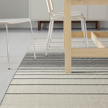 Un tapis tissé à plat à rayures horizontales noires et blanches tendance.