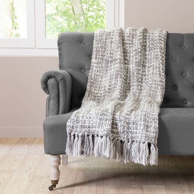 Un plaid en tricot couleur gris argenté avec pompons.
