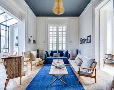 Un grand salon lumineux avec un plafond peint en gris Pour donner l'impression d'un plafond moins haut, le peindre en gris profond alors que les murs sont peints en blancs aide à rendre la pièce plus cosy et déco moderne.