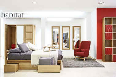 Une chambre déco design chaleureuse entre mobilier rétro et design Un mobilier design fait la déco de cette chambre exposée dans le pop up store Habitat grâce à un lit avec rangements, un fauteuil rétro et un meuble avec étagères tendance.