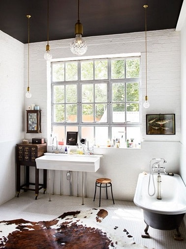 Peindre un plafond en noir dans une salle de bain blanche ça donne du caractère à la déco. Le plafond est assorti à la peinture noire de la baignoire îlot sur pieds.