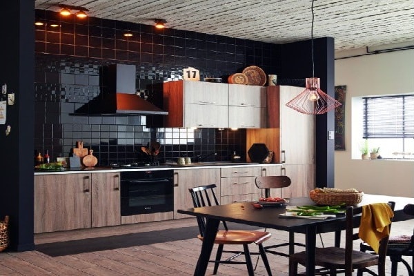 Modernité absolue dans cette grande cuisine ouverte entre carrelage et plan de travail noirs et meubles bois.