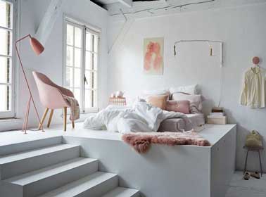 Elégante et lumineuse, une chambre parentale blanche qui s'enveloppe de douceur avec une belle couleur rose poudré pour le tapis et les coussins. 