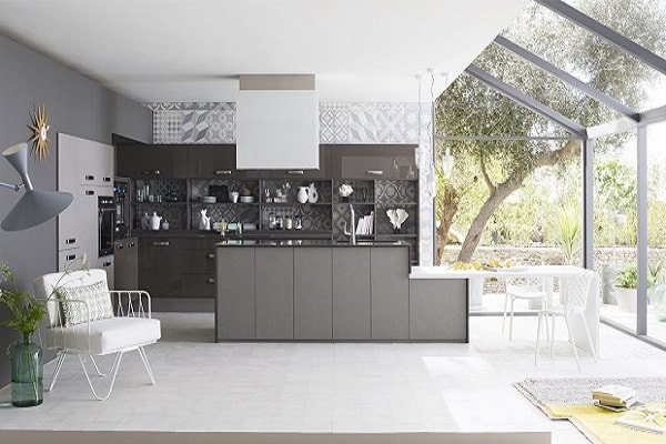 Une cuisine complètement ouverte et moderne avec îlot gris et meubles de cuisine anthracite. Déco papier peint vinyle carreaux de ciment.