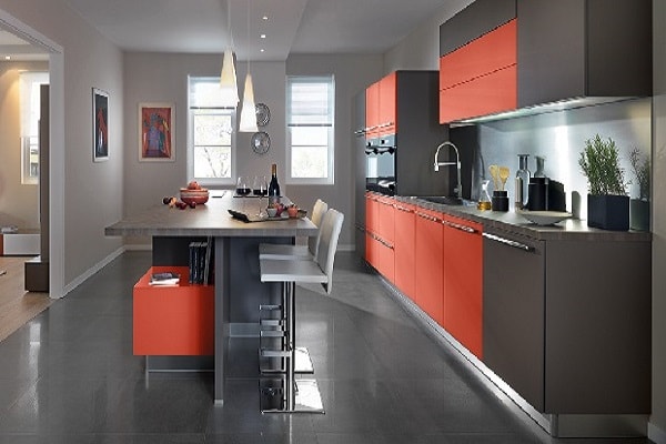 Cette cuisine ouverte sur la pièce à vivre adopte des couleurs modernes rouge et gris sur les meubles.