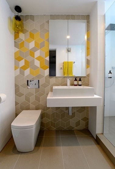En quête d'originalité, le mur de ces cabinets met en lumière des carreaux de ciment cubiques. Beige avec des touches de jaune, cette déco WC stylée est pleine de peps. 