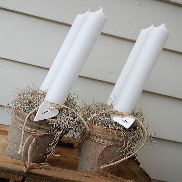 Des vieux pots en terre authentique avec des grands cierges blancs pour décorer la maison ou le balcon à Noël.