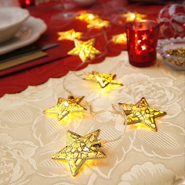 Utiliser une guirlande lumineuse avec étoiles comme déco Noël sur une table de réveillon est une idée pour réchauffer l'atmosphère, la déco et sublimer l'argenterie.