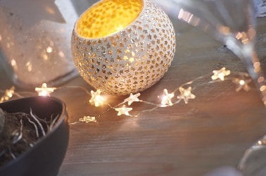 Entre les bougies et autres lanternes de la table, cette guirlande fine avec des décorations petites étoiles met en lumière l'élégance et la convivialité de la déco de Noël.