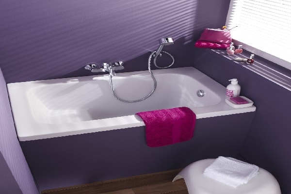 Un baignoire sabot dans une salle de bain violette.