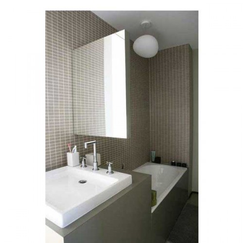 Dans une petite salle de bain en longueur, du carrelage et une peinture gris taupe avec une petite baignoire blanche encastrée
