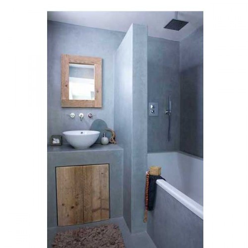Dans béton gris clair et une baignoire blanche qui se transforme en douche italienne dans une petite salle de bain aménagée gaine de place avec un placard de rangement sous le plan vasque construit sur mesure
