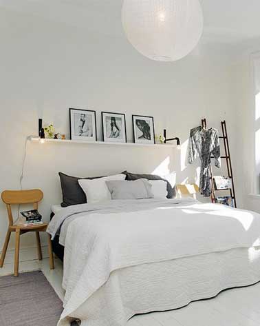 une tête de lit simplissime dans une chambre blanche avec cadre photo sur étagère