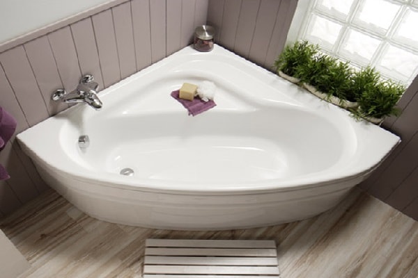 Une baignoire d'angle de forme amande avec rebord pour s'asseoir.