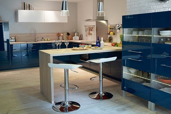Des meubles bleus associés à un plan de travail bois ça donne un aménagement de cuisine ouverte moderne et chic.
