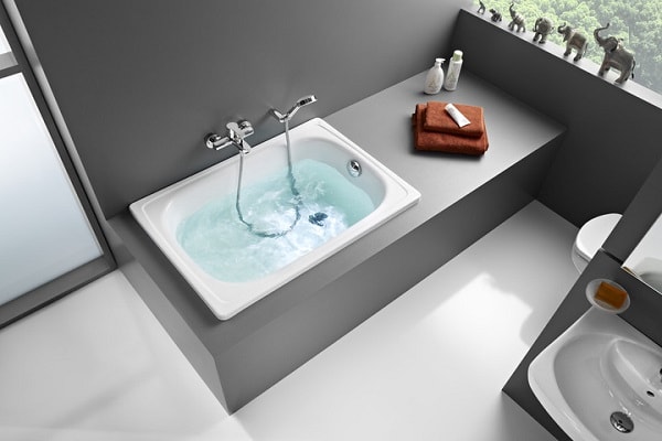 Une micro baignoire sabot dans une salle de bain grise.