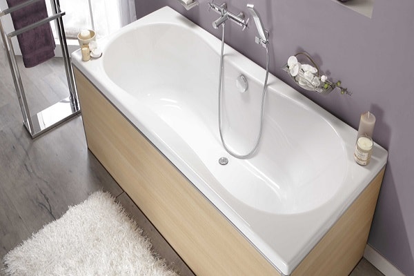 Une petite baignoire forme haricot et revêtement bois.