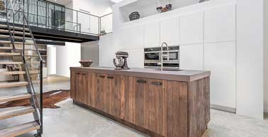 Ilot central en bois effet vieillit pour réchauffer cette cuisine ouverte d’inspiration loft contemporain. Un décor saisissant et unique réalisée par La Cuisine Française.