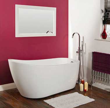 Décor blanc et rose pour la petite baignoire ilot de la salle de bain. Peinture couleur rose foncée et parquet en bois foncé. Baignoire 949 € Hudson Reed 