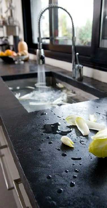 Béton ciré noir sur le carrelage du plan de travail dans une cuisine industrielle. Le rendu du béton ciré et les tons noirs font la déco design de la cuisine