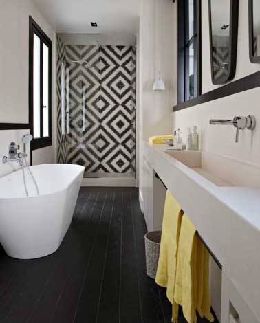Une salle de bain noire et blanche graphique avec des carreaux de ciment posés sur le mur de la douche italienne. Pour contraster un carrelage au sol noir.