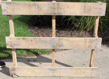 Pour démonter l'arrière de la palette en bois, on recommence la même opération en retirant les clous des planches de bois du haut vers le bas.