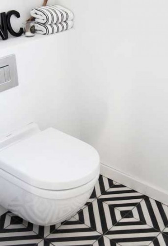 Belle harmonie déco dans ces toilettes blanche. Les carreaux de sol noirs et blancs aux motifs très forts s’imposent sous le bloc cuvette wc suspendu.