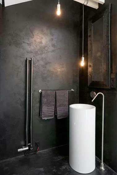 Une douche italienne contemporaine en béton ciré noir. L'effet brut du revêtement béton est souligné par deux spots et les détails design de la colonne vasque