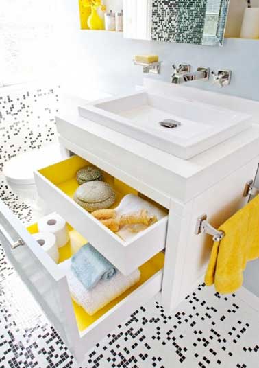 Le jaune une couleur joyeuse dans une petite salle de bain blanche. Elle investit l'intérieur des tiroirs du meuble blanc avec de l'adhésif, les objets déco