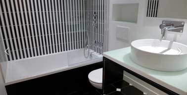Noir et blanc : un tandem couleur chic dans une petite salle de bain. Le carrelage à rayures verticales posé sur la baignoire apporte de la hauteur à la pièce